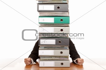 Desperate business woman sits behind folder stack
