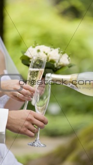 Somebody fills newly-married couple's glasses with champagne