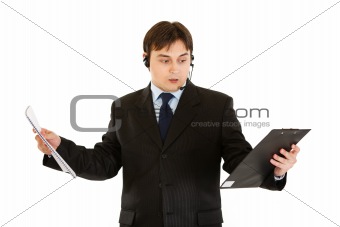 Stressed modern businessman with headset holding documents in hands
