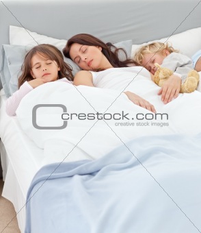 Serene mother sleeping with her children in her bed