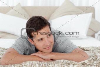 Happy man lying on the edge of his bed