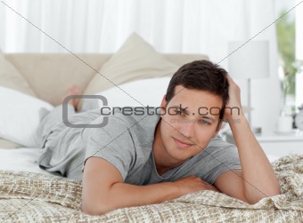 Thoughtful young man lying on his bed