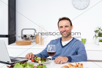 Happy man working on his laptop while having lunch