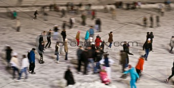 Winter skating rink in the evening with moving people