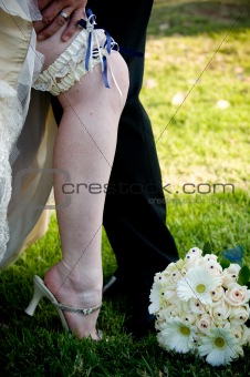 Grooms hand on bride's leg with blue and white garter exposed