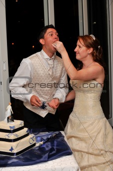 Bride feeding the groom wedding cake with her hand and smiling