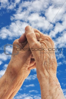 Hands of senior woman over sky