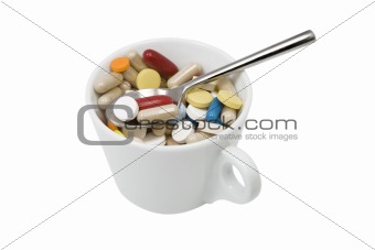 cup of multicolored tablets and capsules with spoon