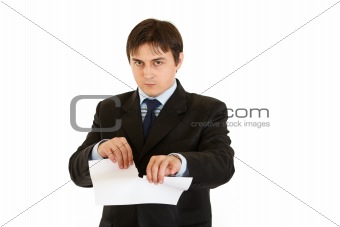 Displeased modern businessman tearing document
