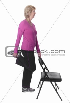 Active senior woman doing leg stretch with chair