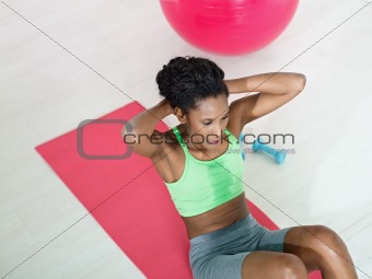 african woman doing series of crunch in gym