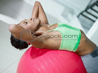 african woman doing series of sit-ups in gym