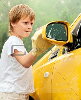 Little boy washing yellow car.