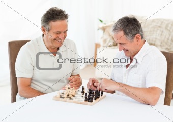 Senior men playing chess at home