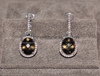 Elegant jewelry earrings with topaz and brilliants over textile 
