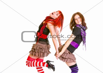 Two pretty cheerful girls standing back to back and holding hands
