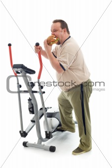 Overweight man eating by an exercising device