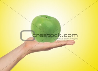 green apple on the hand over yellow