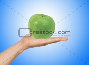 green apple on the hand over blue