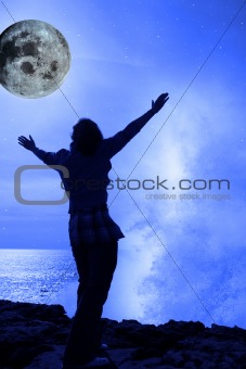 a woman with raised hands facing a wave and full moon on cliff e