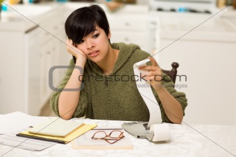 Multi-ethnic Young Woman Agonizing Over Financial Calculations in Her Kitchen.