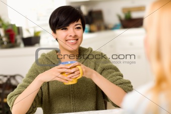 Multi-ethnic Young Attractive Woman Socializing with Friend in Her Kitchen.