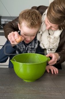 Boy and mother making the dough for the cakes