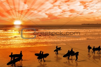 surfers walking on glorious sunset beach
