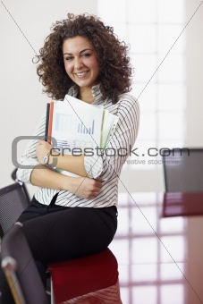 Pretty secretary with charts smiling at work