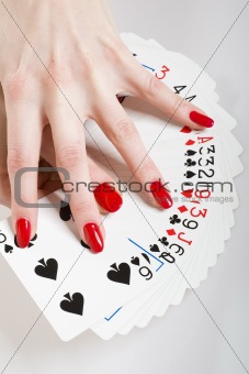 Beautiful hands with perfect red manicure holding a deck of play