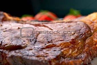 Macro of grilled meat ribs on white plate with tomatoes