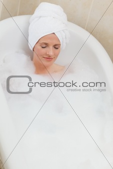Lovely woman taking a bath with a towel on her head 