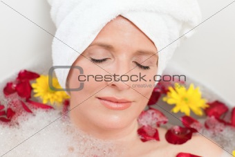 Relaxed woman taking a relaxing bath with a towel on her head 