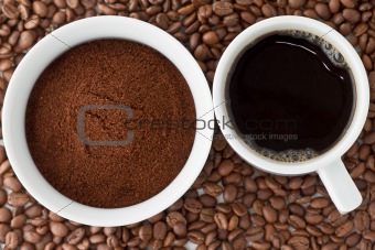 Coffee power in bowl and coffee in cup on top of coffee beans