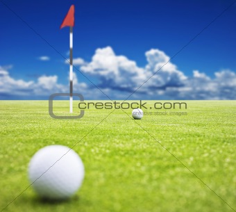 Golf ball on a putting green with  the flag in the background - very shallow depth of field