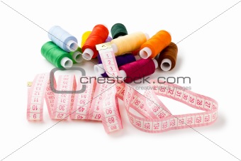 Spools Multi-colored threads randomly with a measuring tape of the tailor isolated on a white background