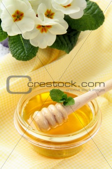 fresh golden honey in jar with a wooden spoon and flowers