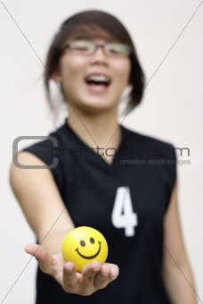 Excited asian lady holding yellow happy ball in hand
