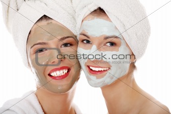 Young happy women with facial clay mask 