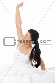Happy young woman stretching in bed
