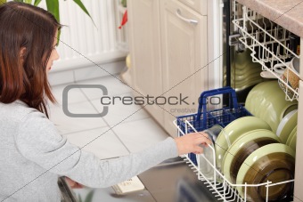 Young woman in kitchen doing housework.