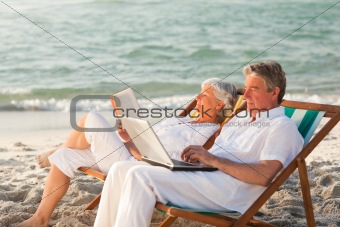Woman reading while her husband is working on his laptop