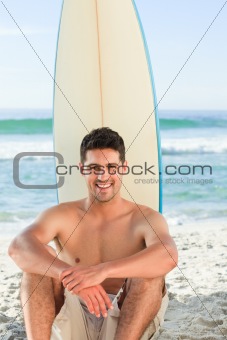 Handsome man with his surfboard at the beach