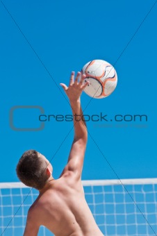 young boy playing volleyball on beach