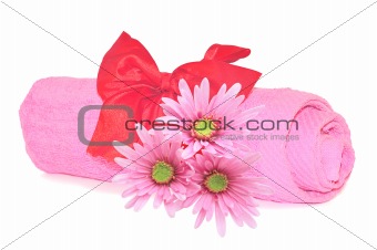 Twisted pink towel with red ribbon bow and pink flowers isolated