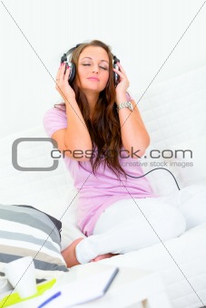 Pretty woman relaxing on couch and listening music in headphones
