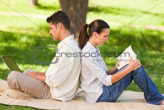Man working on his laptop while his wife is reading