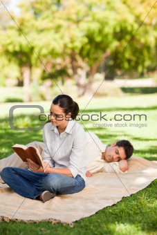 Woman reading while her husband is sleeping