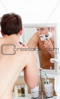 Handsome caucasian man shaving in the bathroom