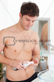 Positive caucasian man ready to shave in the bathroom